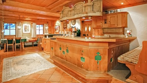 A wooden interior with a bar area, dining space, and a large rug.