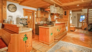 A wooden interior with a kitchen area, a dining table, and a staircase leading to another level.