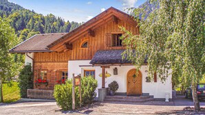 A traditional wooden chalet with a white facade, a tiled roof, and a small porch area.