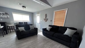Ein modernes Wohnzimmer mit zwei schwarzen Sofas, einem Esstisch und Stühlen.