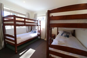 A room with two bunk beds, a small bedside table, and a window with curtains.
