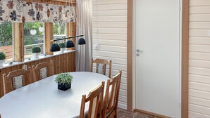 Comedor con mesa redonda, sillas de madera, planta en maceta e iluminación colgante.