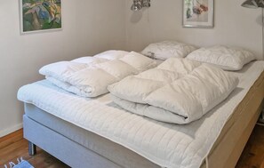 Ein Bett mit einer gesteppten weißen Bettdecke und Kissen, einem grauen Kopfteil und einem Holzboden.