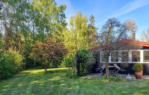 Ein Wohngarten mit einem Haus, einer Pergola und verschiedenen Bäumen.