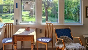 A room with a table, two chairs, a window with a view of a garden, and a hanging light fixture. - 2 bedroom cozy home in Jægerspris (Jægerspris)