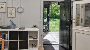 A room with a bookshelf, a clock, and a door leading outside. - 2 bedroom cozy home in Jægerspris (Jægerspris)