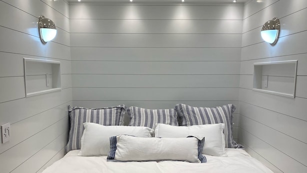 A neatly arranged bedroom with a large bed, white bedding, and two wall-mounted light fixtures.