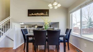 A dining area with a table and chairs, a cityscape artwork on the wall, and a staircase leading to another level. - 2 Master Suites with King beds fast Wifi (Centennial)