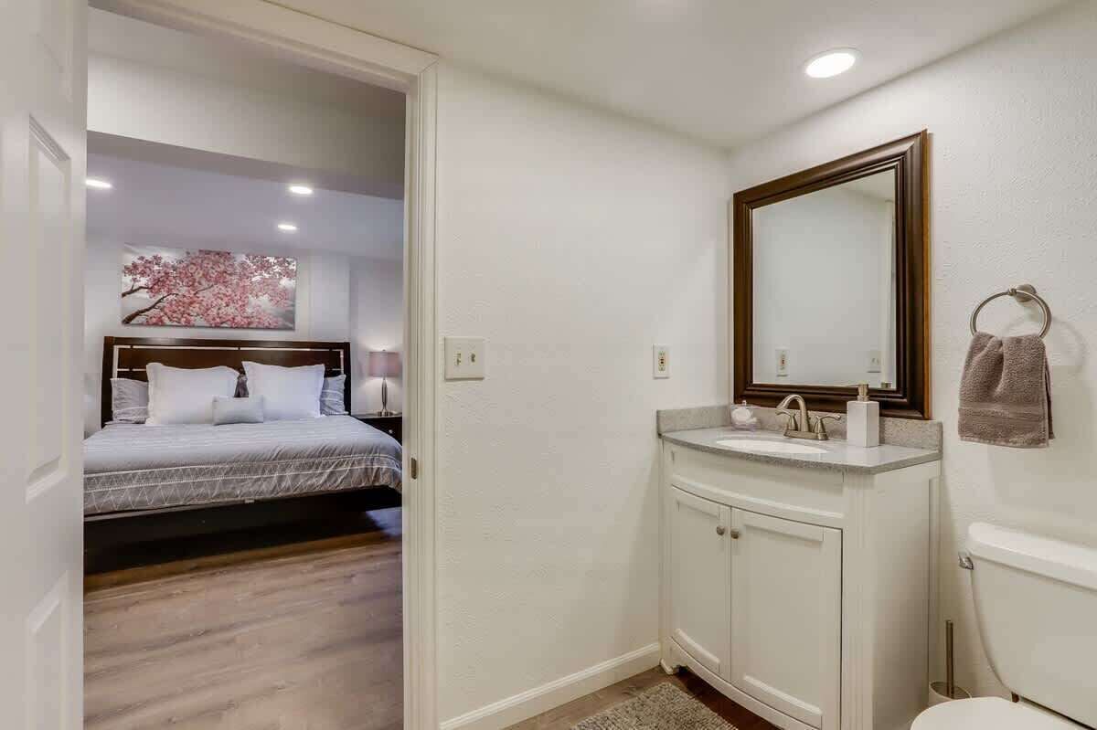 Un dormitorio con cama y un baño con lavamanos e inodoro.
