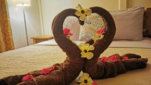 A neatly made bed with a heart-shaped towel arrangement and scattered flowers. - Casa mindanao apartments, AC+WIFI + swimming pool. (Limon)