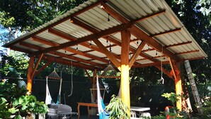 A covered outdoor area with a wooden pergola, a grill, and hanging hammocks. - Casa mindanao apartments, AC+WIFI + swimming pool. (Limon)