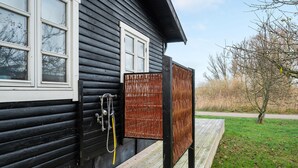 Ein schwarzes Holzhaus mit einem weißen Fenster und einer Holzterrasse.