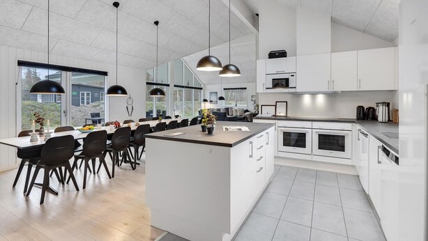 Een moderne keuken met witte kastjes, een centraal eiland en hanglampen.