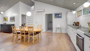 A modern kitchen with white cabinets, a built-in oven, and a sink. There is a dining area with a wooden table and chairs. - Pet friendly home in Gistrup with WiFi (Gistrup)