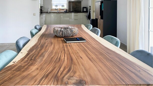 Un tavolo da pranzo con un originale disegno venato sul legno, circondato da sedie, in una cucina dal design moderno.