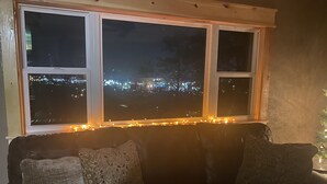 A cozy room with a window overlooking a cityscape at night, adorned with string lights. - City Overlook cabin  (Pigeon Forge)
