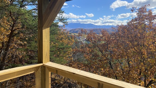 A wooden balcony with a view of autumn foliage and distant mountains. - City Overlook cabin  (Pigeon Forge)