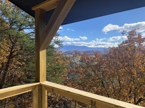 Ein hölzerner Balkon mit Blick auf Herbstlaub und ferne Berge.