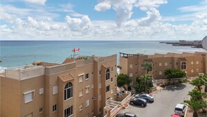 Un hôtel situé sur la côte, composé de plusieurs bâtiments à étages, doté d’un parking et offrant une vue sur la mer.