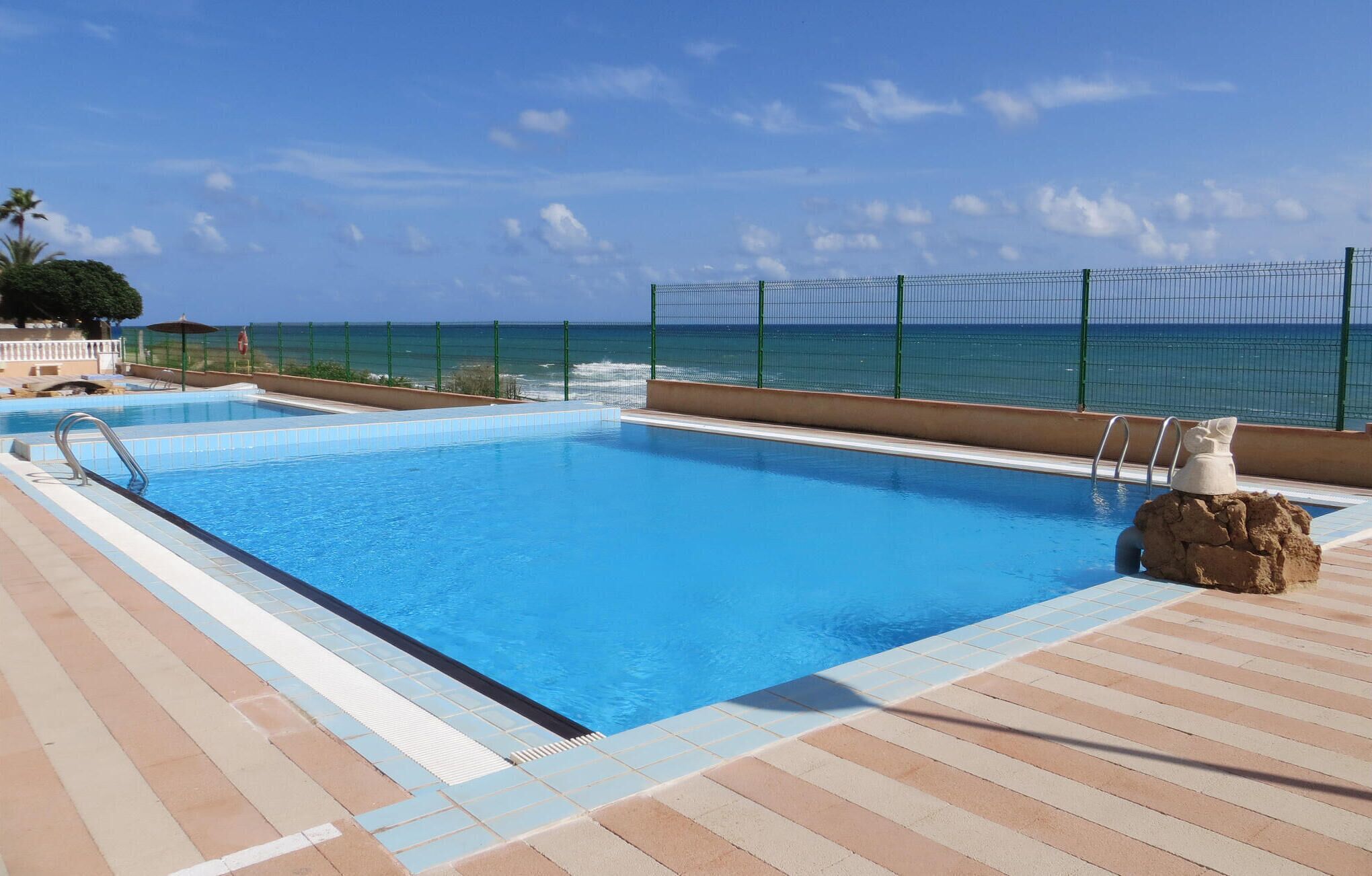A swimming pool with a view of the ocean, a lifeguard chair, and a stone sculpture.
