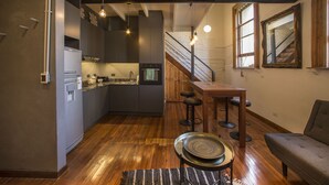 A modern kitchen with a wooden bar and stools, a staircase, and a dining area with a sofa. - YOUR PLACE IN THE HEART OF BUENOS AIRES (CABA)