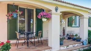 Ein Haus mit einer Veranda, grünen Fensterläden und Blumentöpfen.