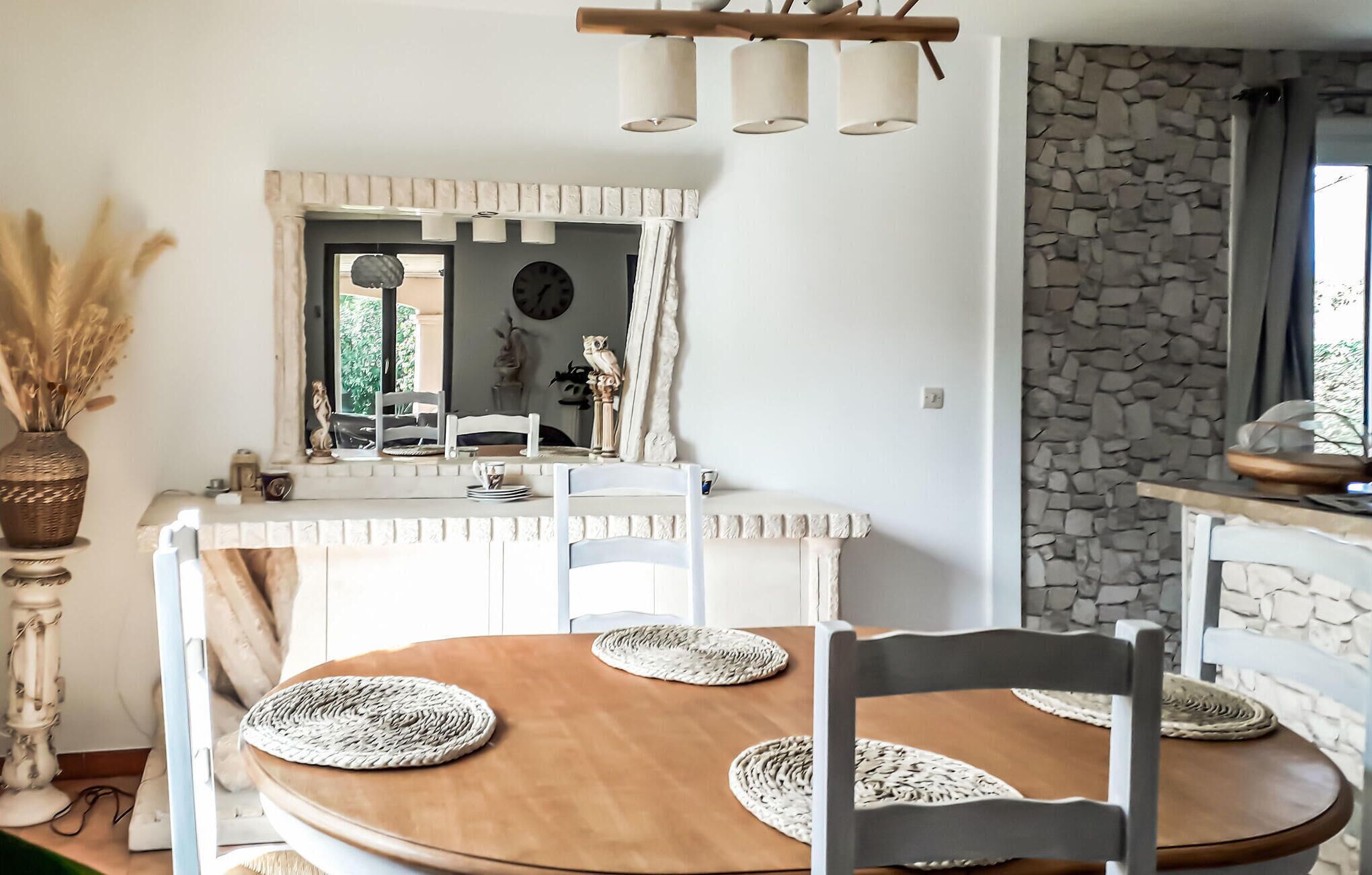 A dining area with a round table, white chairs, and woven placemats.