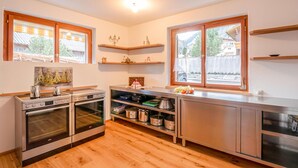 Una cocina moderna con dos hornos, un lavamanos y un ventanal con vistas a una zona residencial.