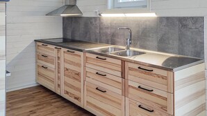 A kitchen with a stainless steel sink, wooden cabinets, and a herringbone-patterned backsplash.