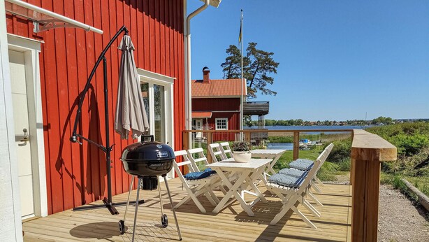 A wooden deck with outdoor seating, a barbecue grill, and a view of a lake.