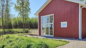 A red wooden building with large windows and a gravel path leading to it.