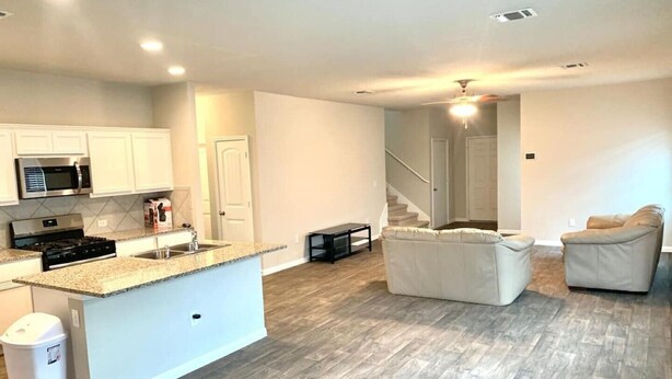 A modern kitchen with white cabinets, a granite countertop, and stainless steel appliances. - Close to downtown 14mint Airport 15 minute and south (Austin)