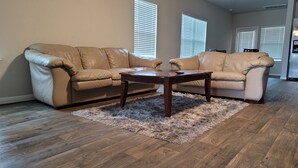 A living room with a beige leather sectional sofa, a wooden coffee table, and a fluffy rug on a wooden floor. - Close to downtown 14mint Airport 15 minute and south (Austin)