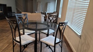 A round glass table with four chairs, a staircase in the background, and a window with blinds. - Close to downtown 14mint Airport 15 minute and south (Austin)