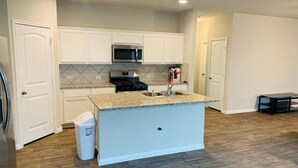 A kitchen with white cabinets, a granite countertop island, a stainless steel microwave, and a gas stove. - Close to downtown 14mint Airport 15 minute and south (Austin)