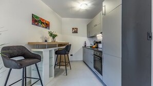 Een moderne keuken met een centraal eiland, barstoelen en een koelkast.