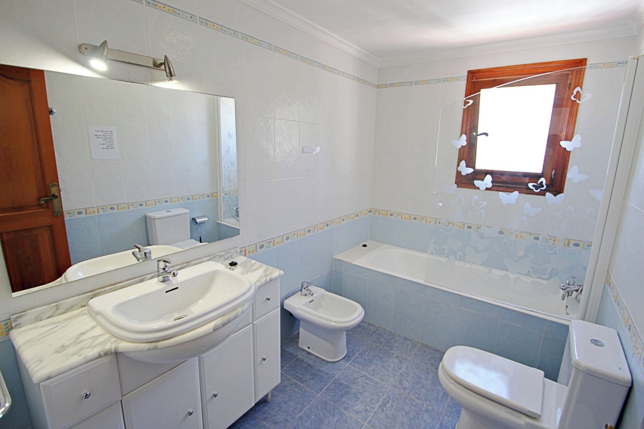 Een badkamer met een wastafel, spiegel, toilet en bad.