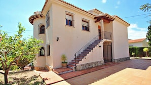 Una casa de dos pisos con un patio adoquinado, una escalera y un pequeño jardín.