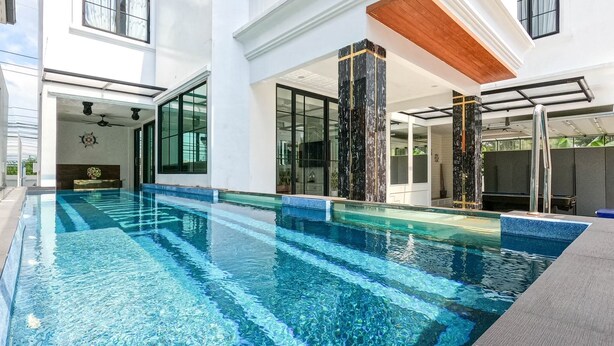 A modern indoor swimming pool with clear blue water, large windows, and a minimalist design. - Exquisite Pool Villa I (Pattaya)
