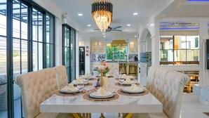 A dining area with a white marble table set for a meal, surrounded by cushioned chairs. - Exquisite Pool Villa I (Pattaya)