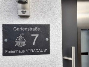 A black sign with white text indicating 'Gartenstraße 7' and 'Ferienhaus *GRADAUS*'.