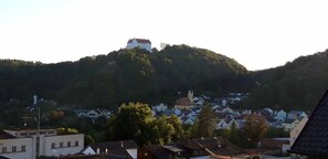 A hilltop castle with a church and residential buildings in the foreground.