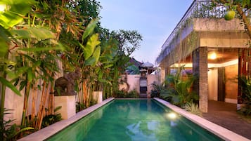 Una piscina al aire libre, sombrillas, sillones reclinables de piscina