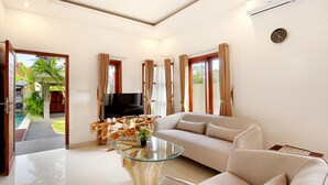A modern living room with a glass coffee table, beige sofa, and a TV. - Askara Villa Uluwatu (Ungasan)