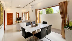 A modern dining area with a white table, black chairs, and a sofa in the background. - Askara Villa Uluwatu (Ungasan)