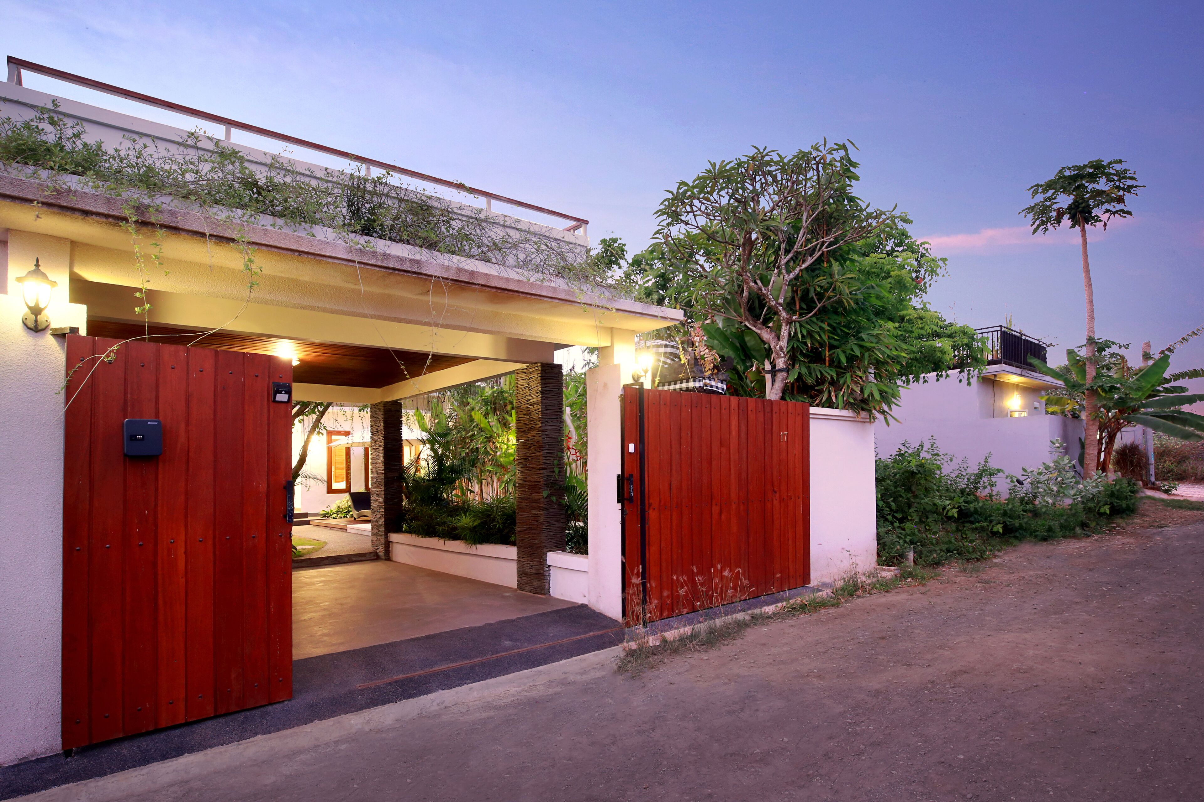 A modern house with a wooden gate, a covered entrance, and a well-maintained garden.