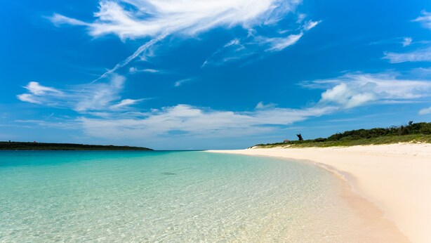 A beach with clear turquoise water and a sandy shore.