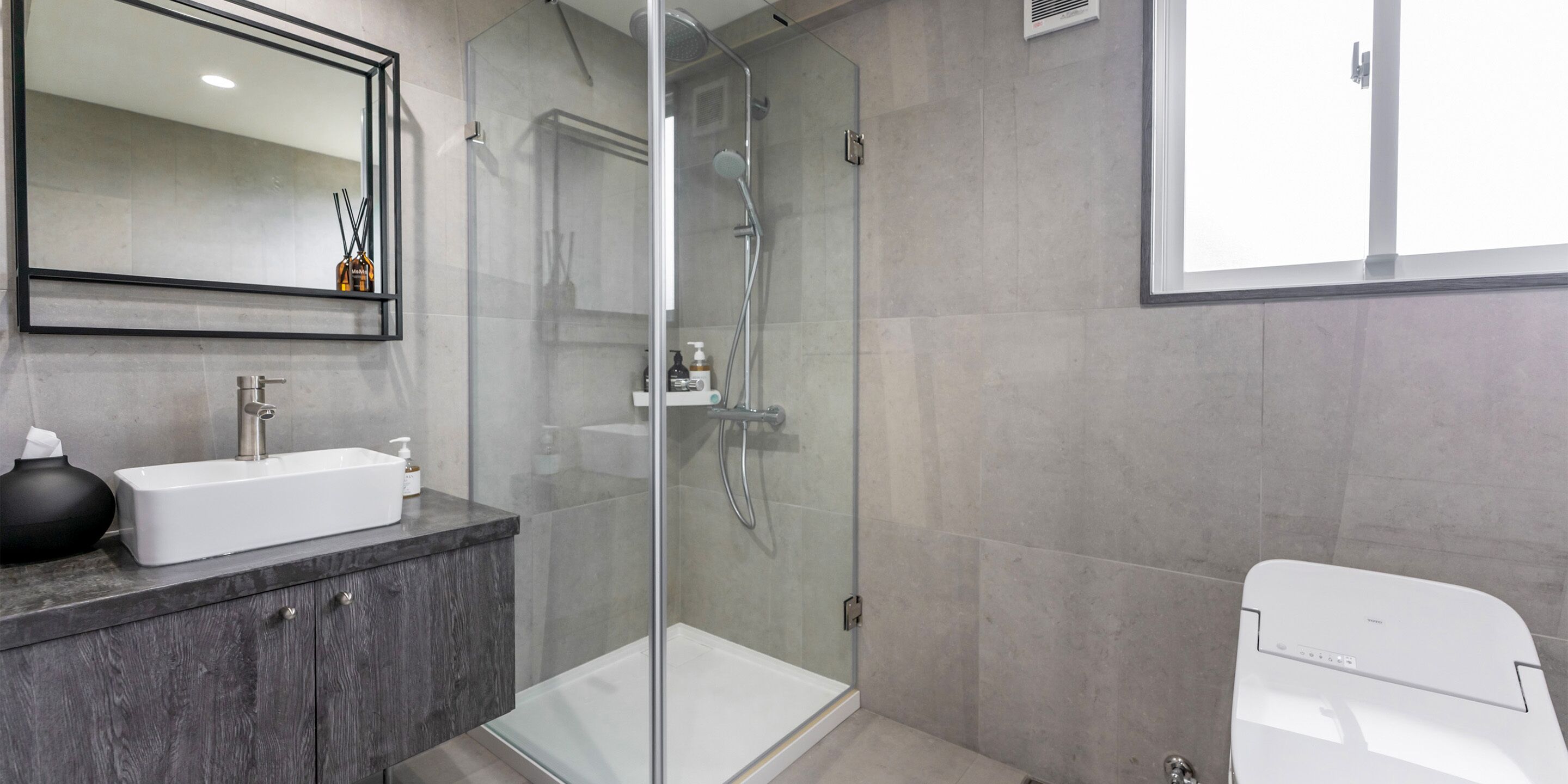 A modern bathroom with a glass-enclosed shower, a white sink, and a toilet.