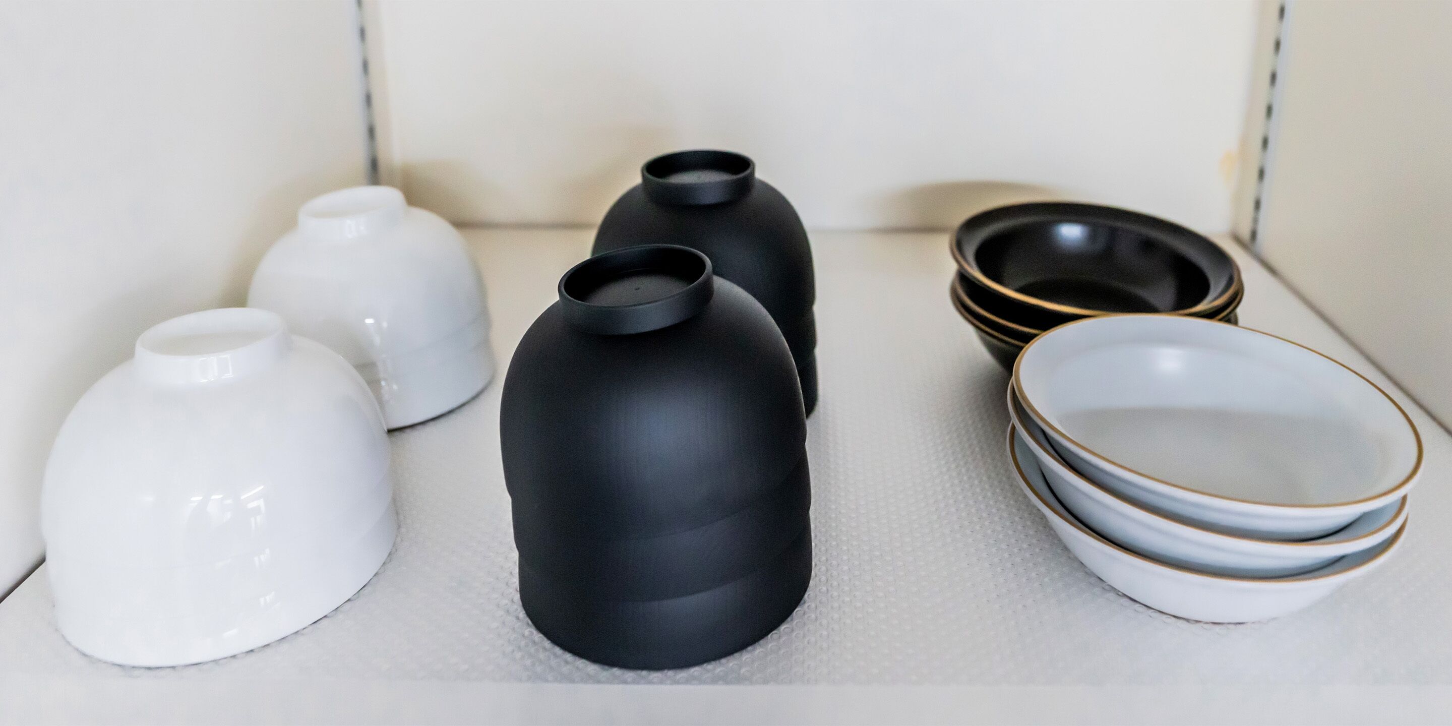 A collection of ceramic vases and bowls arranged on a shelf.