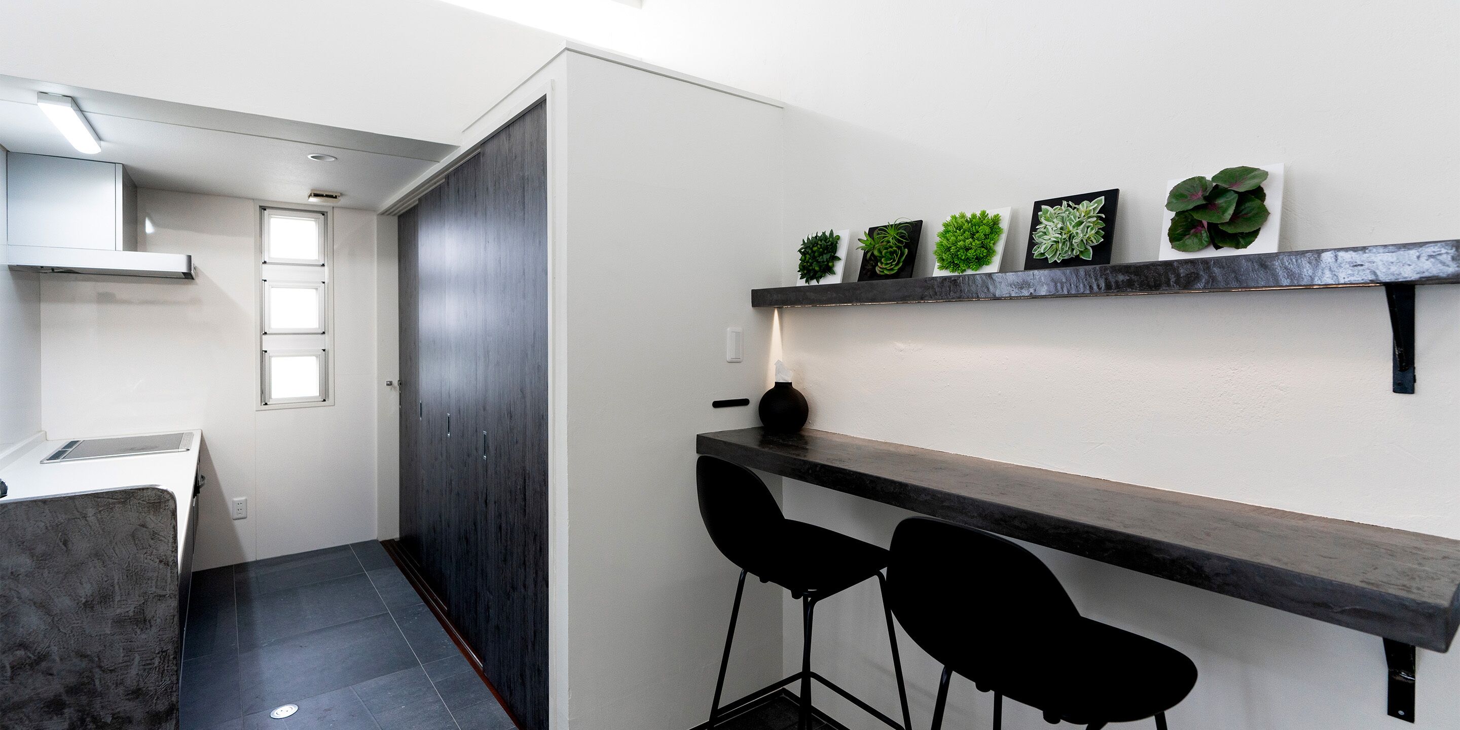 A modern kitchen with a dark wood cabinet, a white countertop, and a black bar stool.
